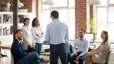 A group of people having a casual meeting in a brick-walled office.